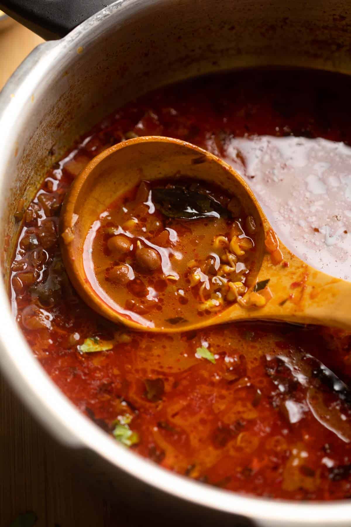 Picture of a ladle of misal being taken out of the pressure cooker