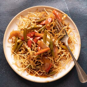 Aemrican Chopsuey served on crispy fried noodles in a white plate with a fork