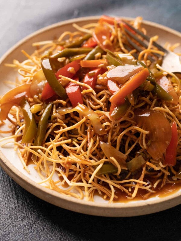 Aemrican Chopsuey served on crispy fried noodles in a white plate with a fork