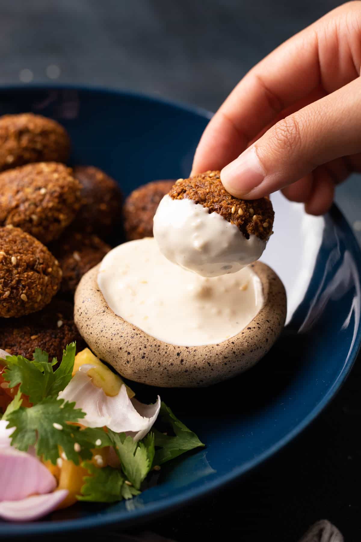 Picture of falafel dipped into tahini sauce
