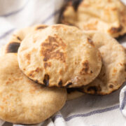 Picture of Whole wheat pita breads kept on a striped white kitchen cloth