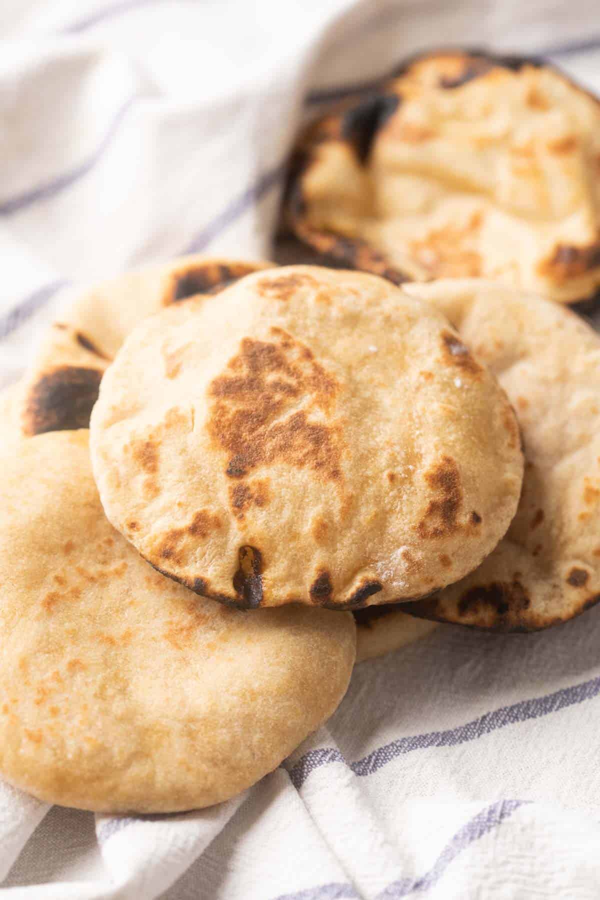 Picture of Whole wheat pita breads kept on a striped white kitchen cloth