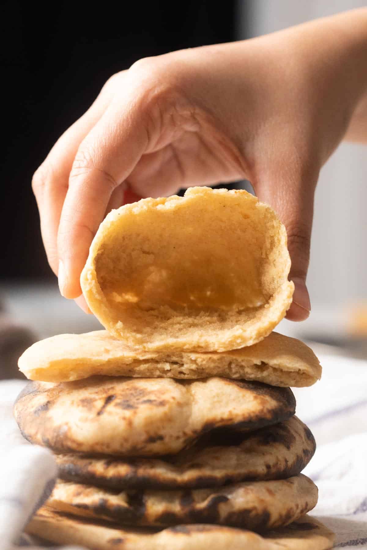 Picture of a hand holding pita open to show the pocket inside