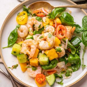 Thai Prawn Mango Salad served on a white plate with cutlery on the side