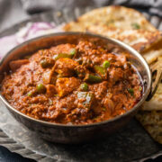 Picture of veg kolhapuri served in a copper kadhai on a plate with onions and naan