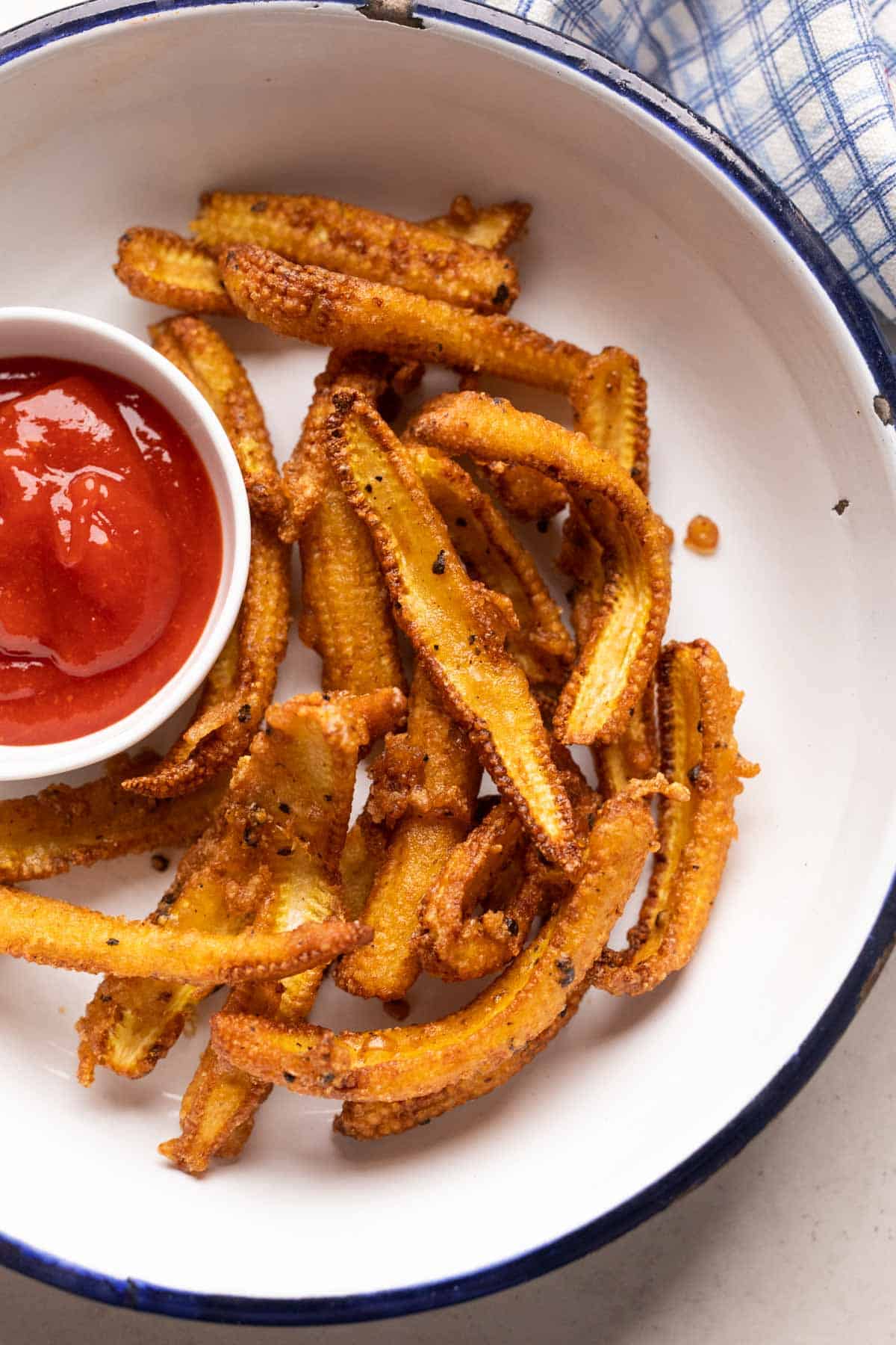Crispy baby corn fry served in a white plate with ketchup on the side