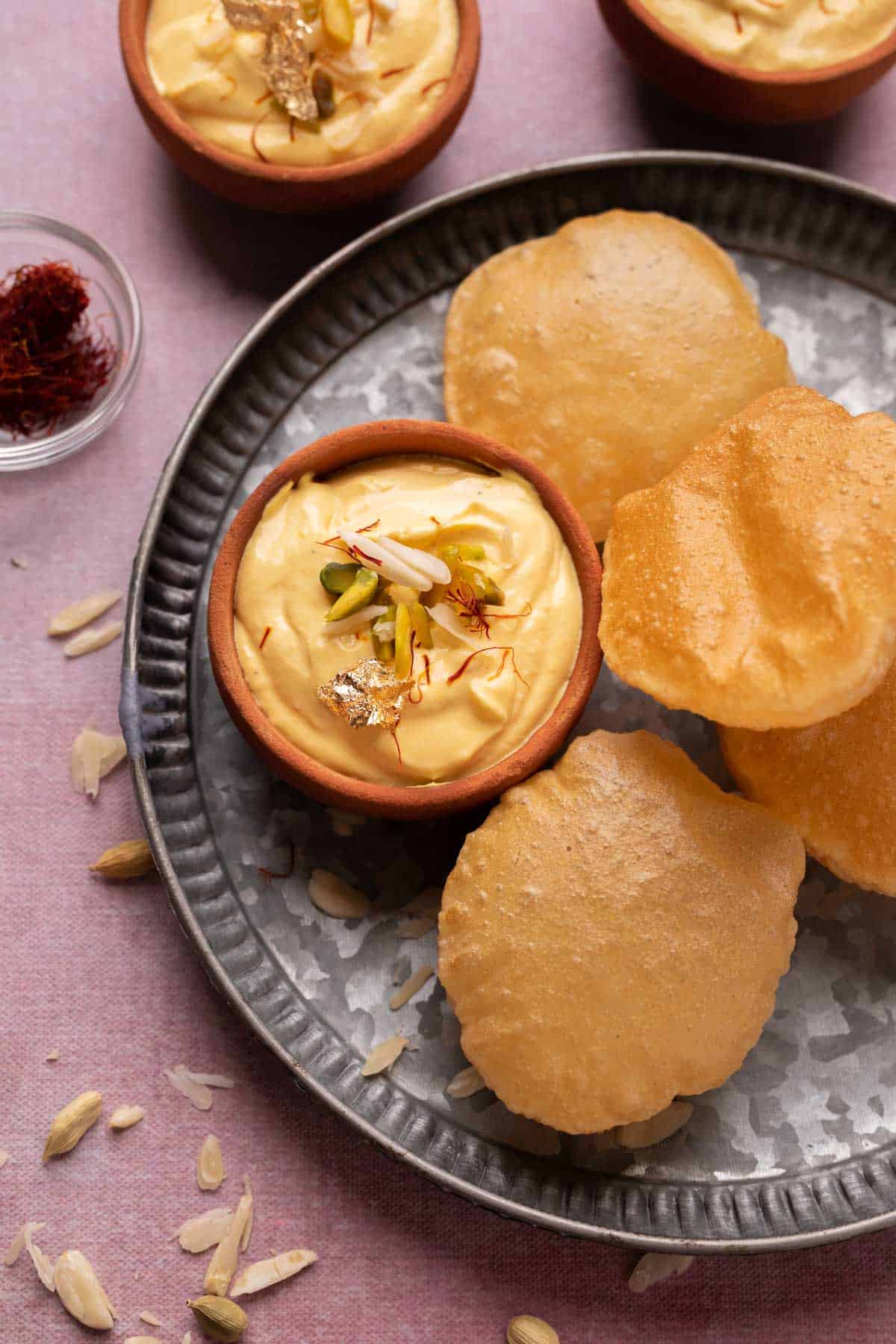Mango Shrikhand served on a plate with pooris