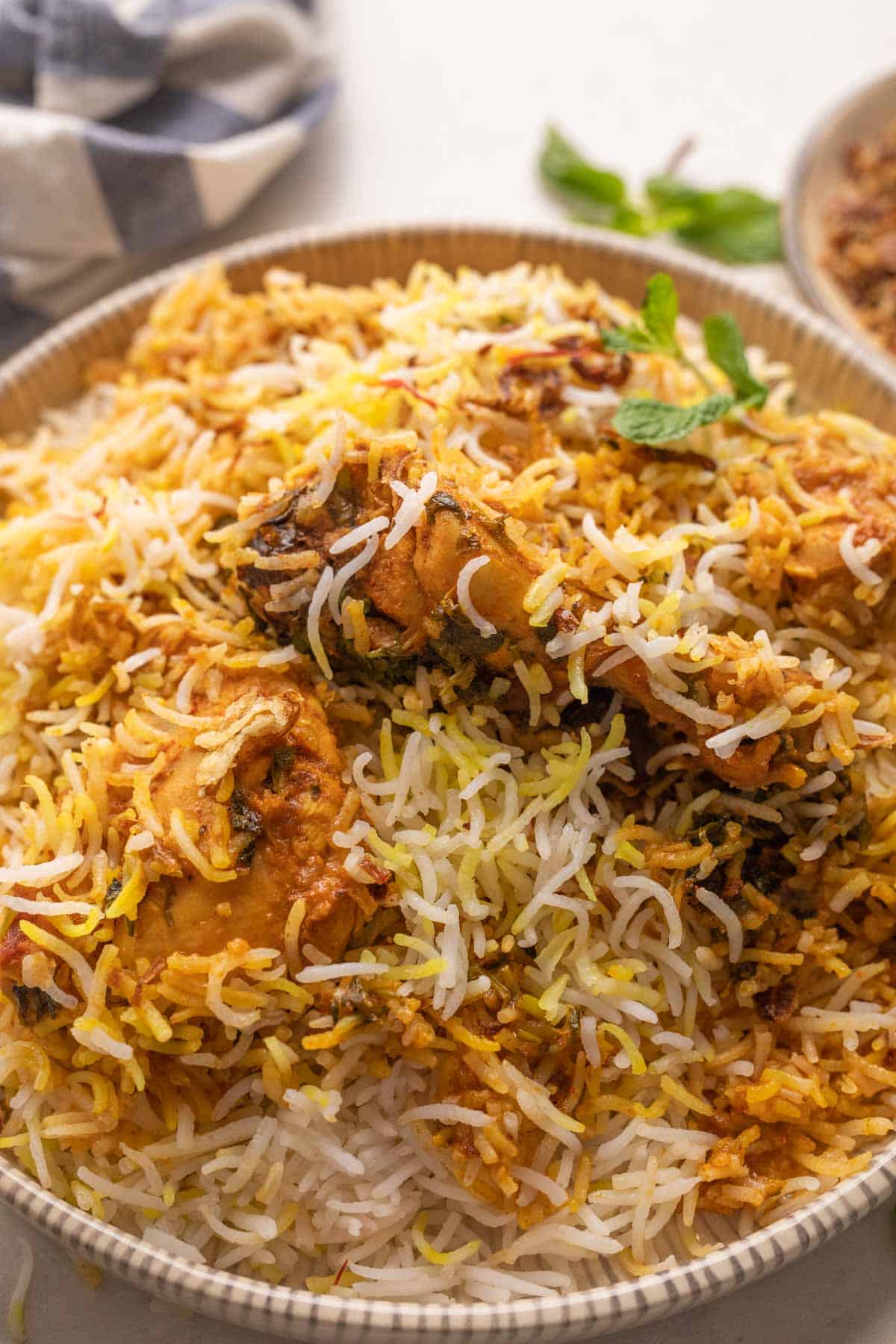 Chicken Biryani served on a plate with fried onions and raita on the side