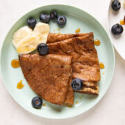 Banana Dosa served on a green kids plate with bananas, honey and blueberries on the side