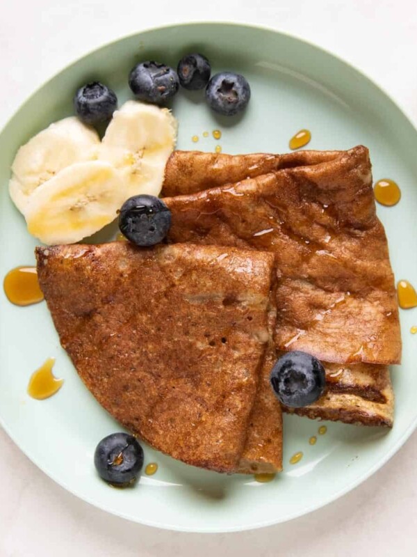 Banana Dosa served on a green kids plate with bananas, honey and blueberries on the side