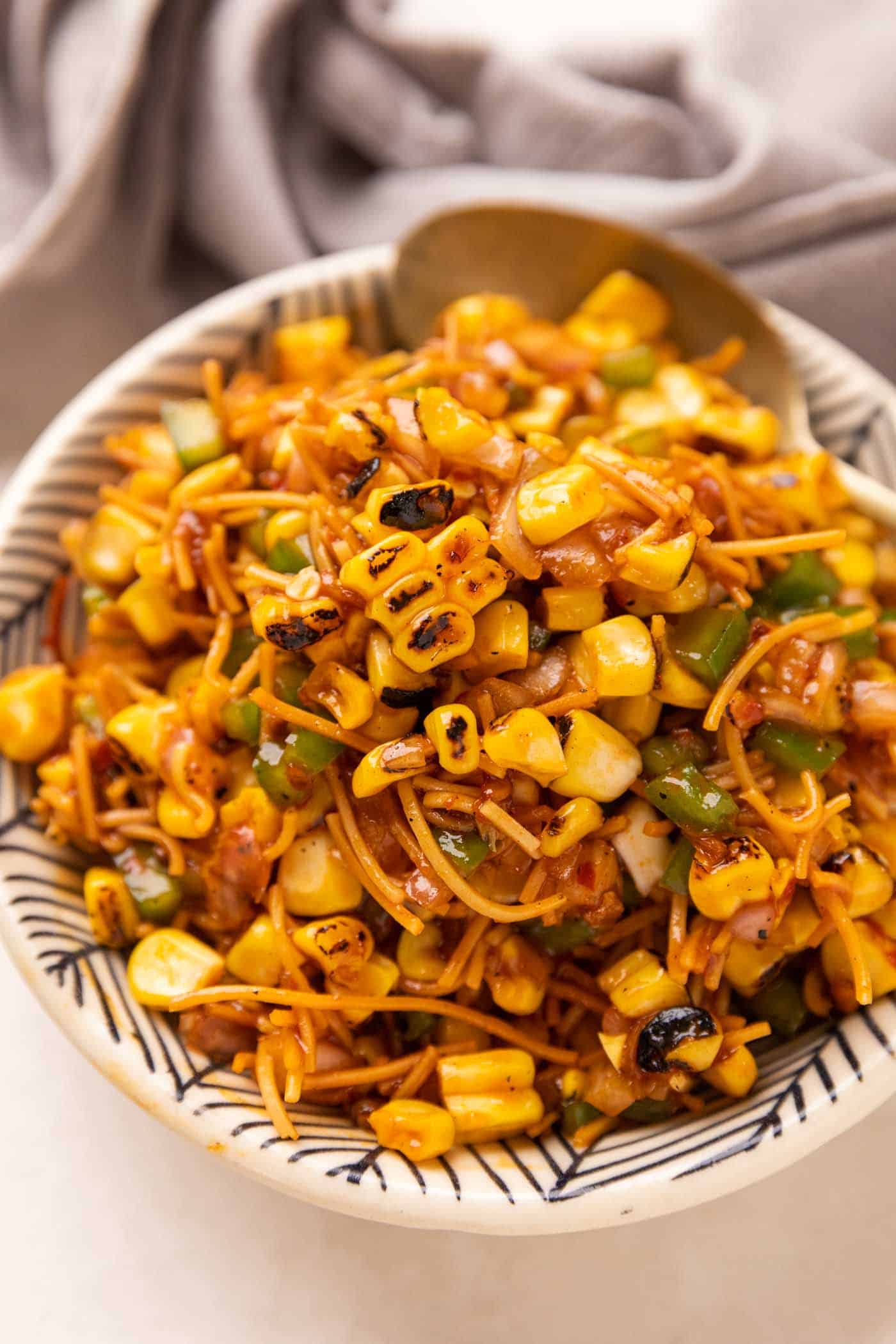 Corn Bhel served in a cowl with a spoon on the side