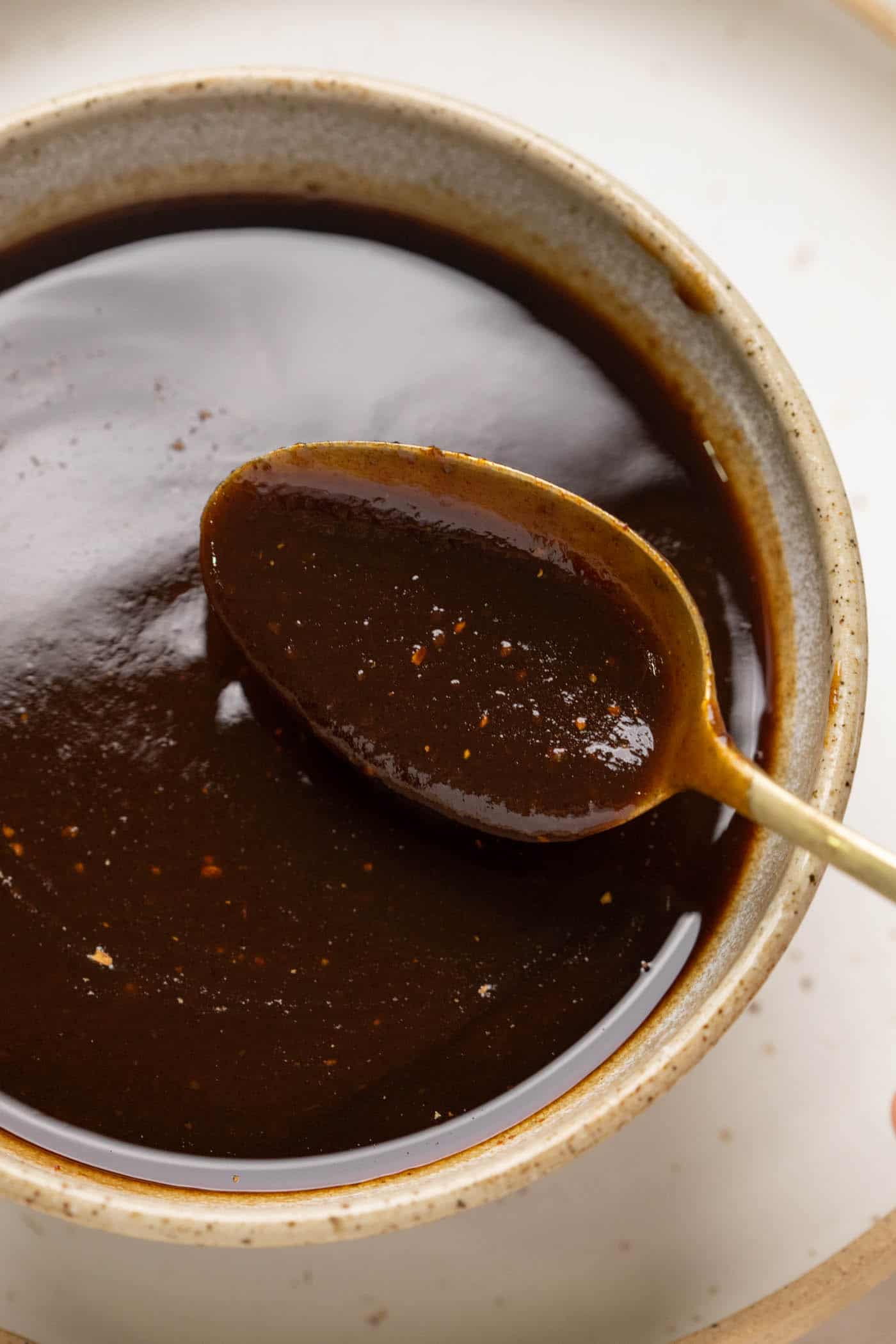 A spoonful of tamarind chutney being taken out of a bowl