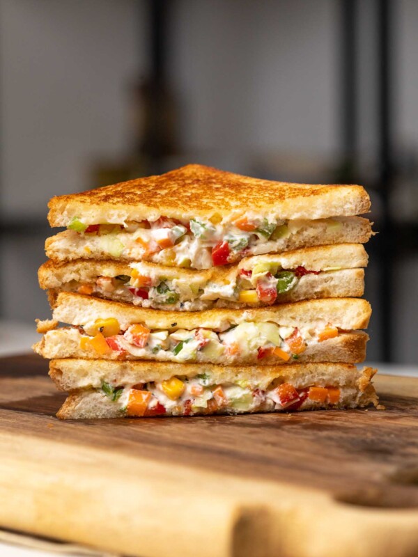 hung curd sandwiches stacked on a wooden chopping board