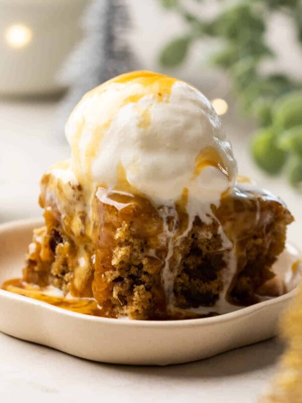 Sticky Toffee Pudding served on a white dessert plate topped with vanilla ice cream and toffee sauce