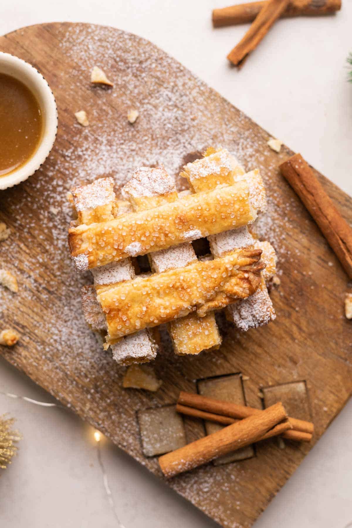 Apple Pie Chips stacked on a wooden board with salted caramel sauce.