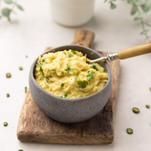Egg and cheese maggi served in a grey bowl with a steel fork.
