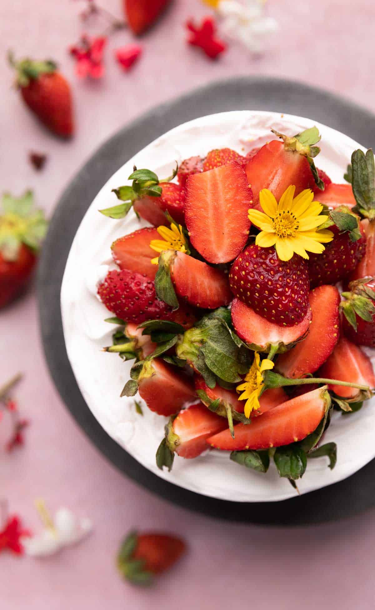 A picture of vanilla cake frosted with whipped cream and topped with strawberries