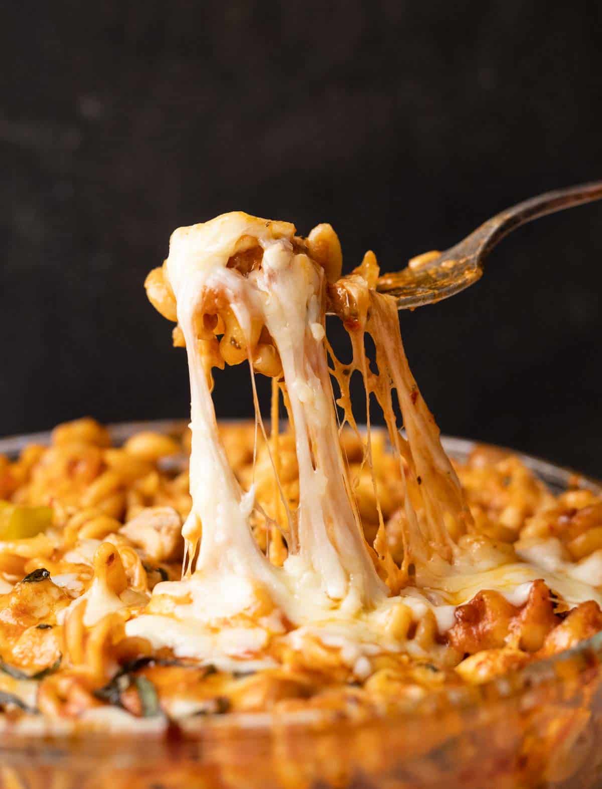 Closeup of air fryer baked pasta in red sauce being eaten with a fork