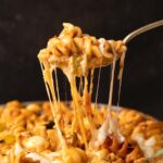 Closeup of air fryer baked pasta in red sauce being eaten with a fork
