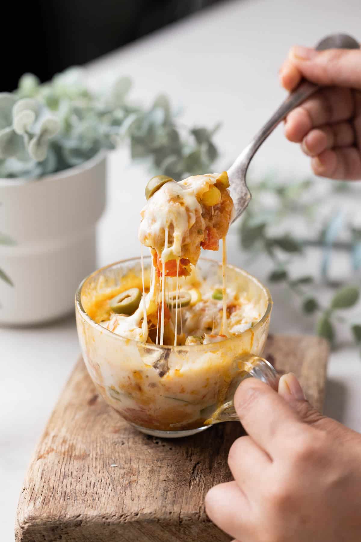 shot of microwave pizza in a mug with a fork full pulled out