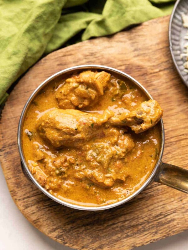 a bowl of coconut chicken curry with a side of jeera rice