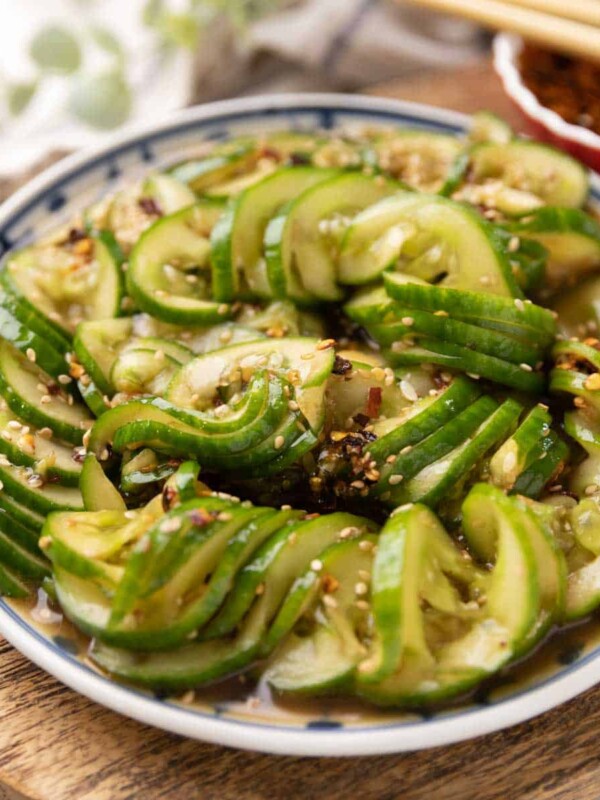 Asian cucumber salad served on a vibrant white and blue plate, featuring sliced Persian cucumbers tossed in a flavourful dressing