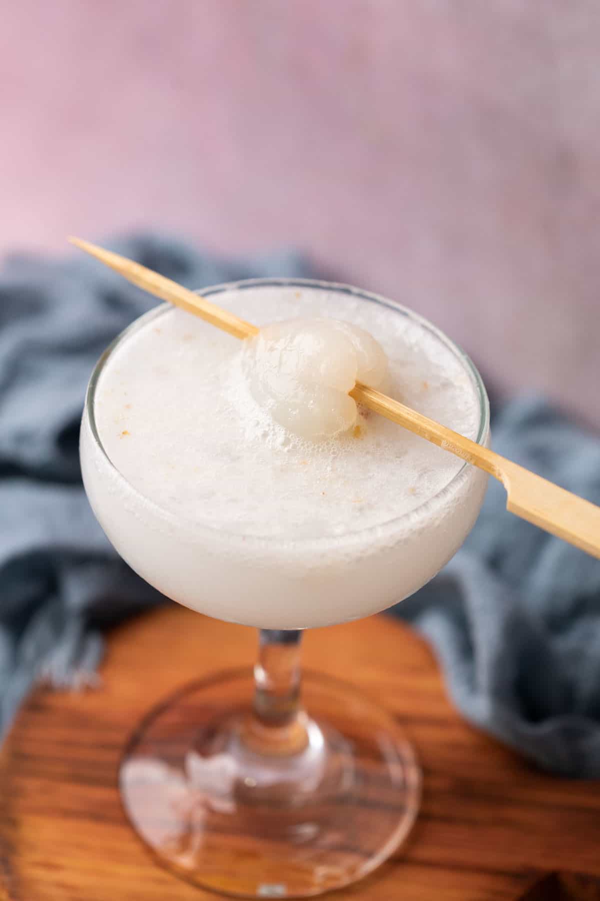 lychee soda served in a glass topped with lychee on a toothpick