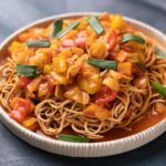 Sweet and Sour Vegetables served on crispy fried noodles in a white plate