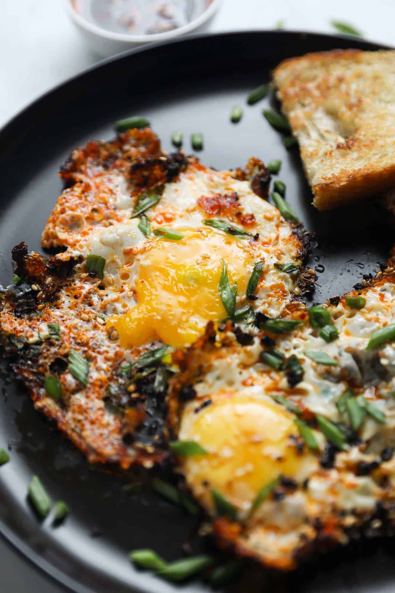 Close up of chilli oil fried eggs on a black plate