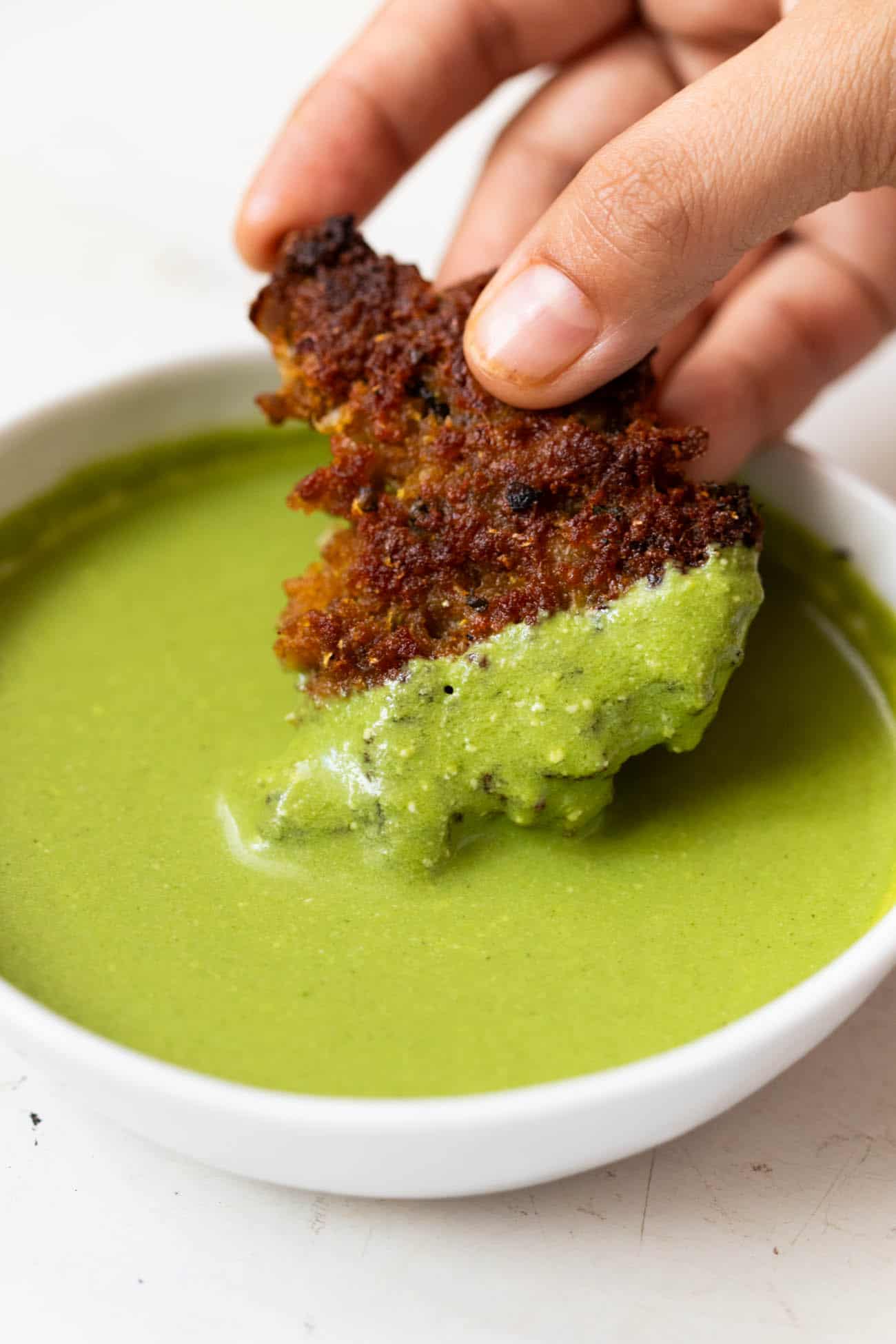 Chapli kebab being dipped into mint chutney
