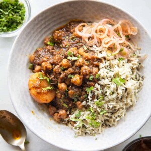 Pressure cooker chana masala served in a bowl with rice and onions on the side