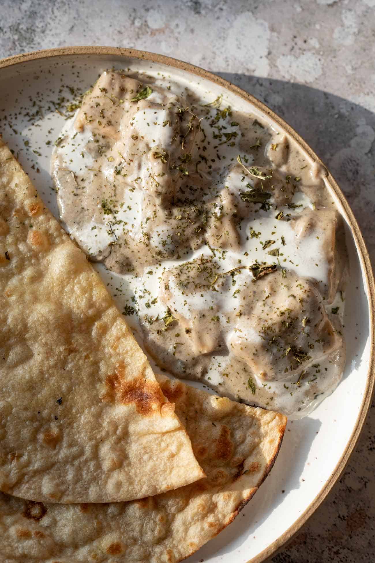 paneer kali mirch gravy served in a bowl with cream drizzled on top served with roti