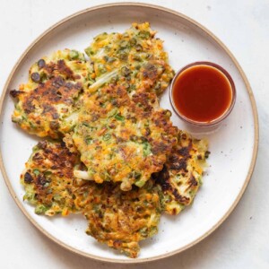 Vegetable pancakes served on a white plate with ketchup on the side