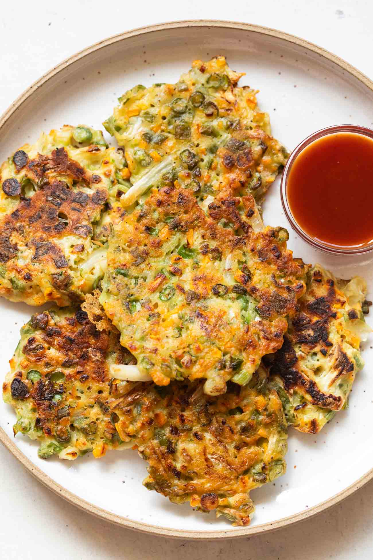 Vegetable pancakes served on a white plate with ketchup on the side