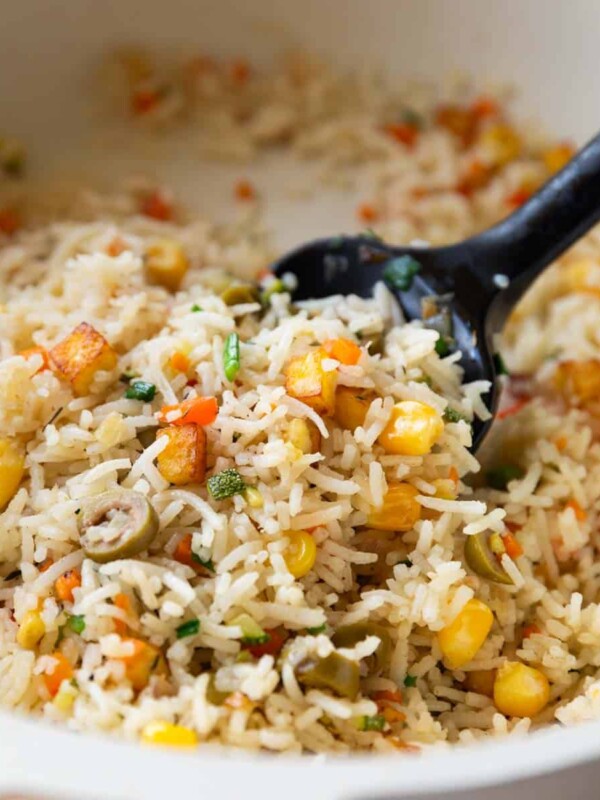 colourful rainbow rice in a white pan with a black rubber spatula