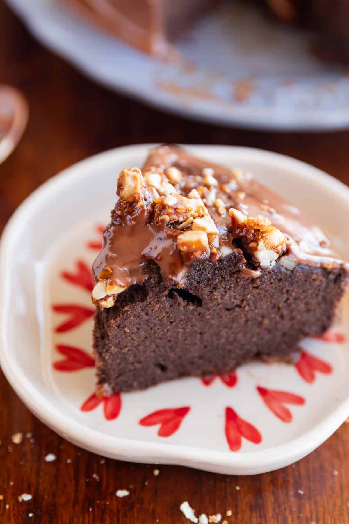 slice of ragi chocolate cake on a white plate with nuts sprinkled on top