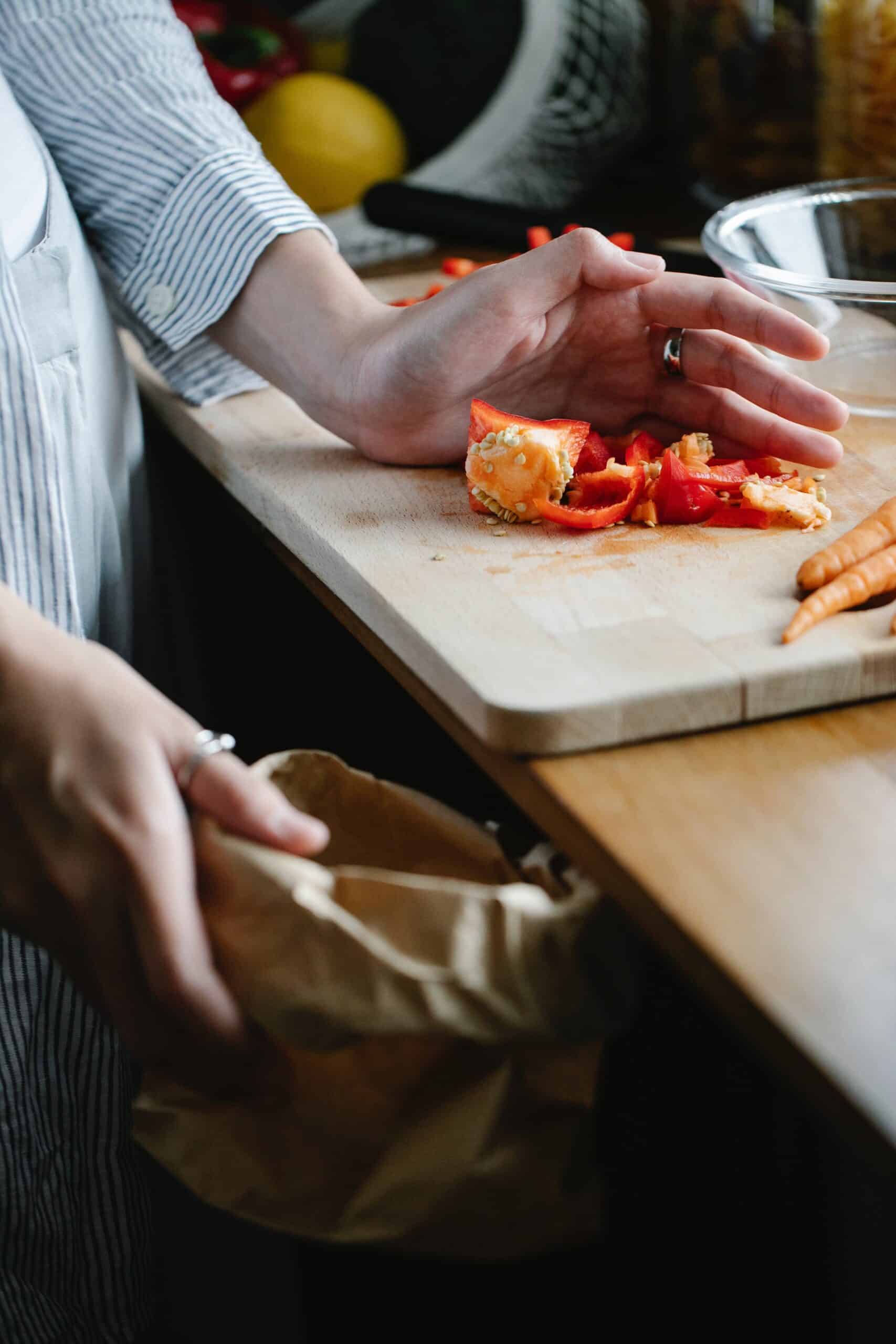 shot of kitchen waste being put into a waste bag