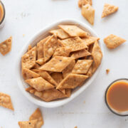 Picture of namak para in a white bowl with cups of chai around it