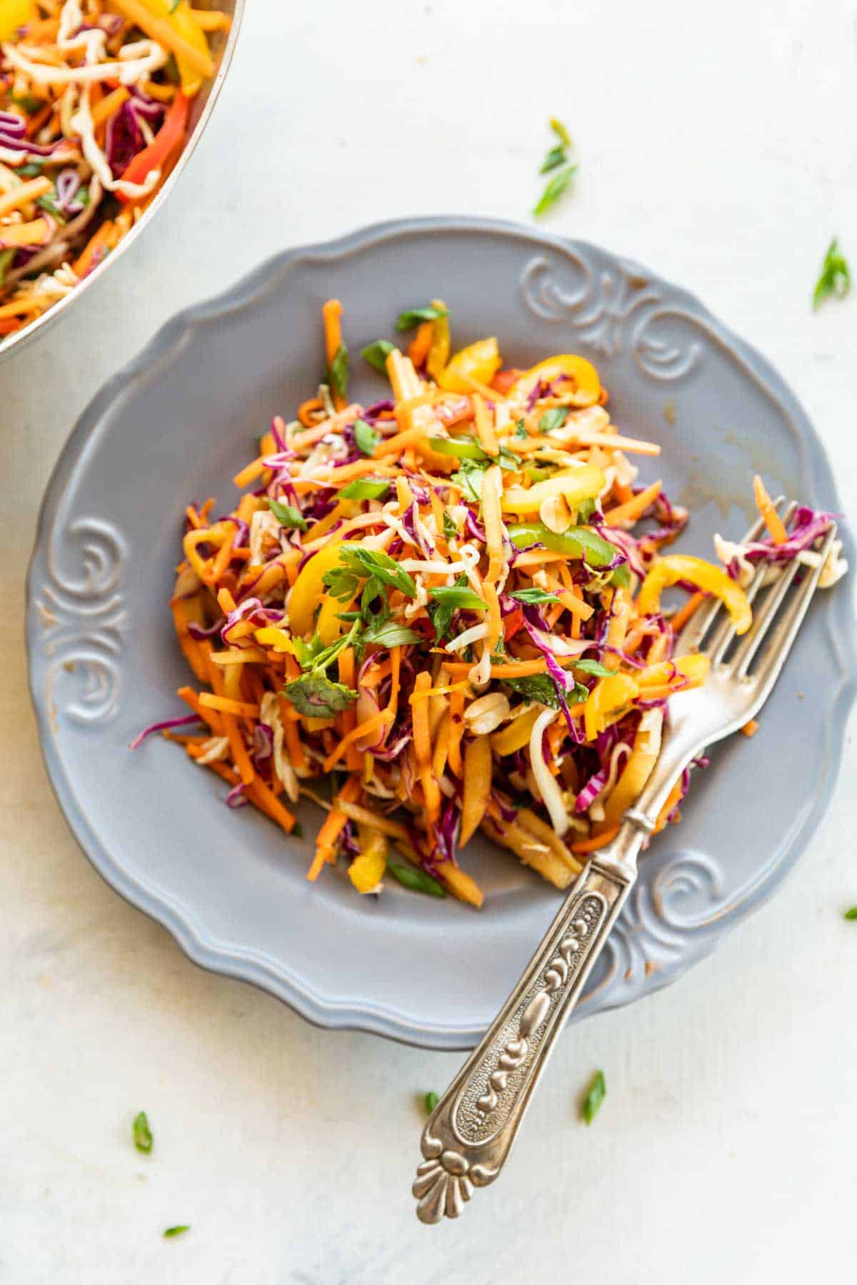 Asian Slaw in a grey bowl with fork on a white background