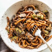 Black pepper udon noodles served in a white bowl with fork