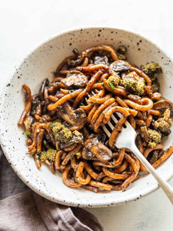 Black pepper udon noodles served in a white bowl with fork