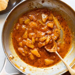 Raw mango chutney in a pan with a spoon and served with pooris