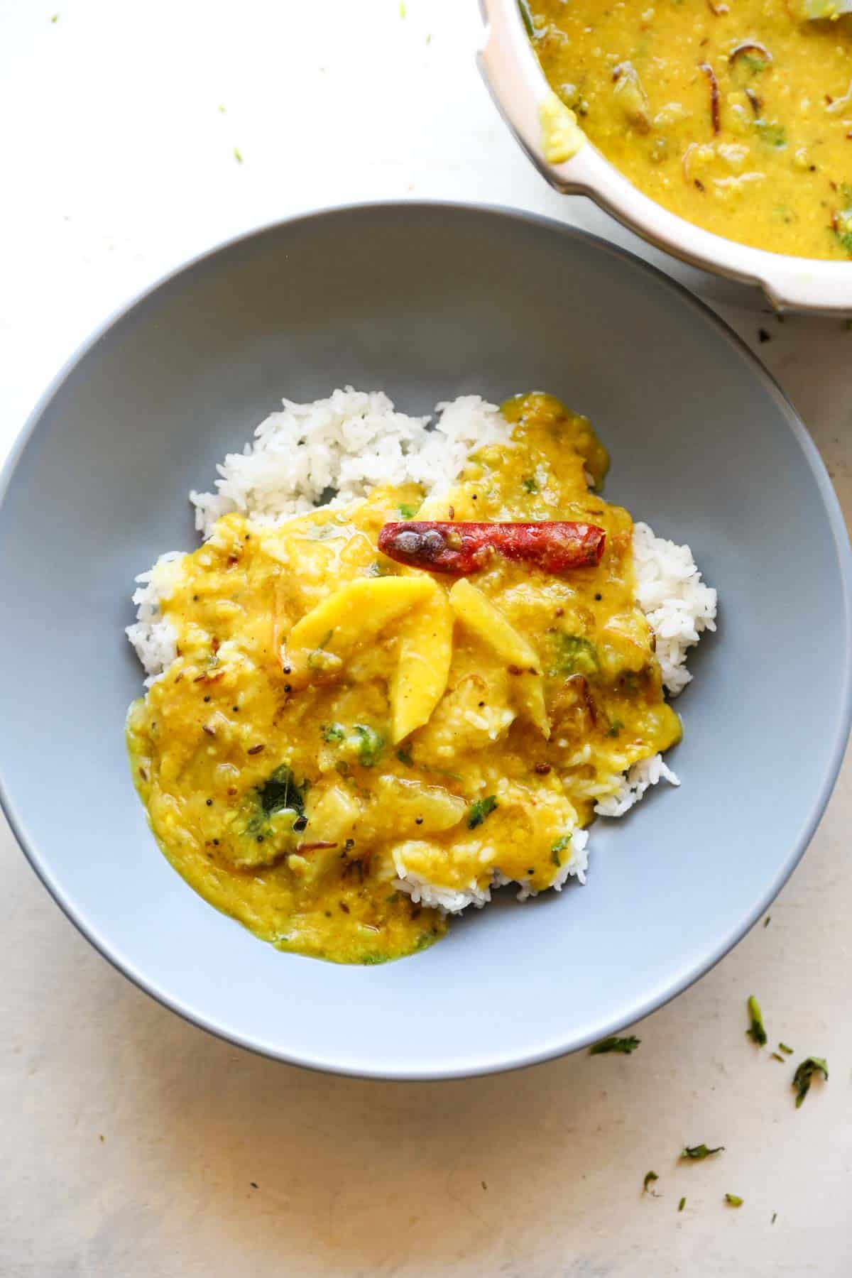 raw mango dal served with rice in a grey bowl