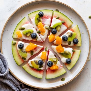 watermelon pizza slices topped with fresh fruits on a white plate