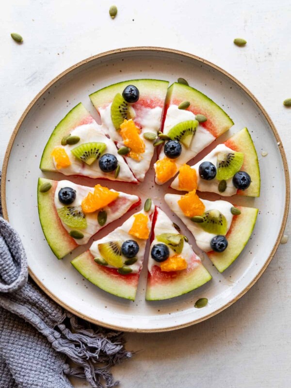 watermelon pizza slices topped with fresh fruits on a white plate