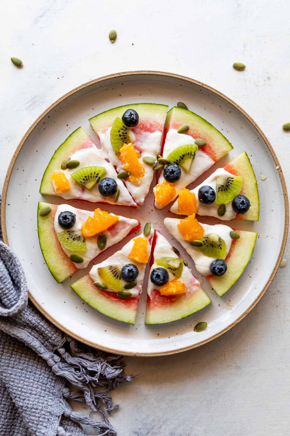 watermelon pizza slices topped with fresh fruits on a white plate