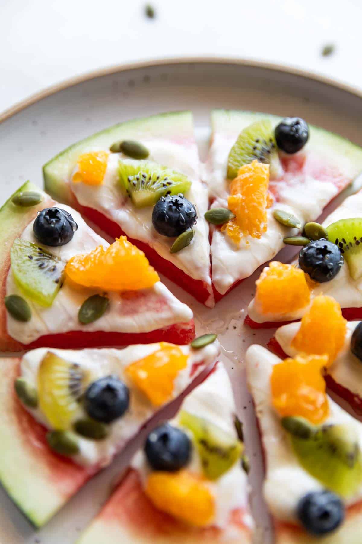 watermelon pizza slices topped with fresh fruits on a white plate