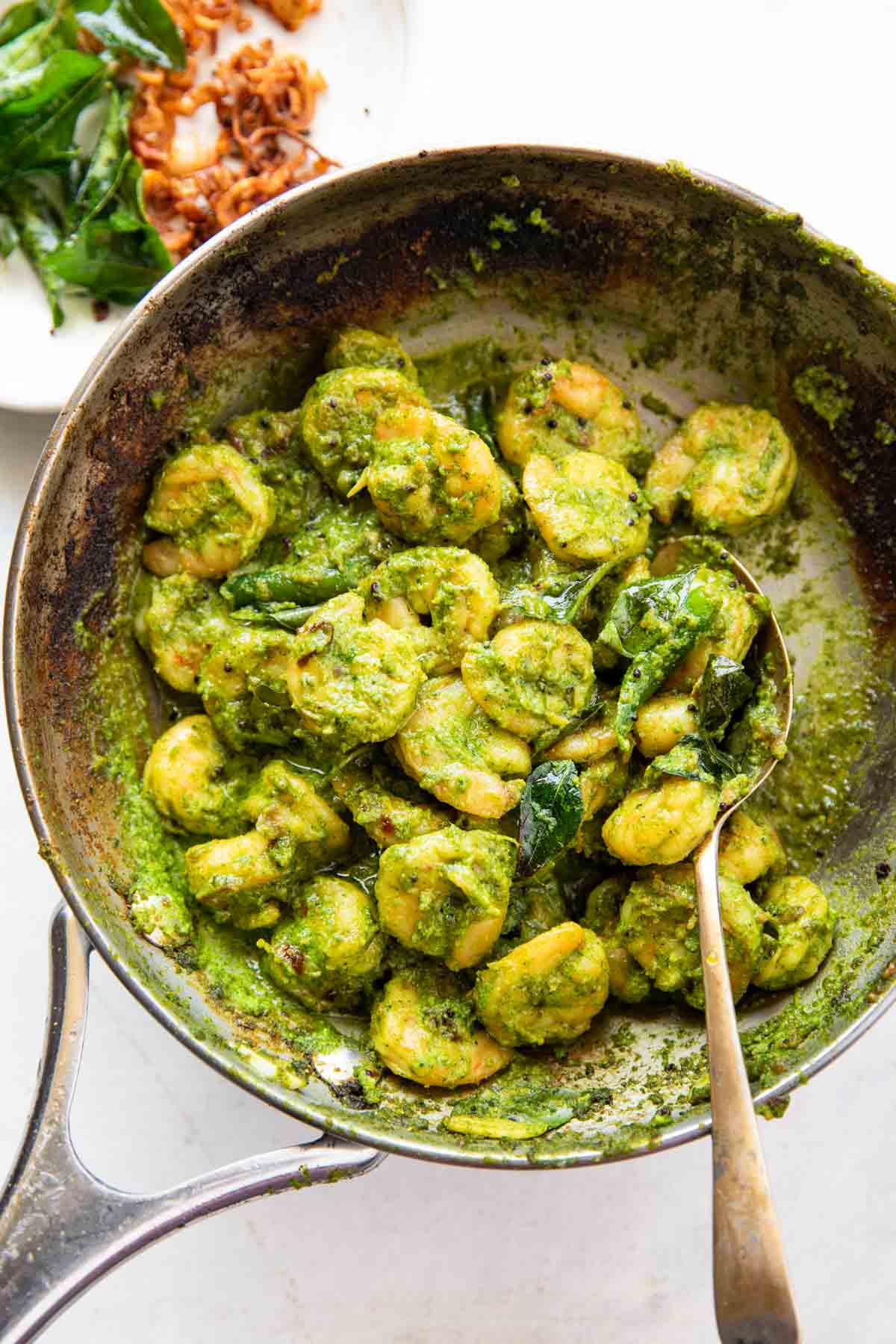 curry leaf prawns in a frying pan with spoon