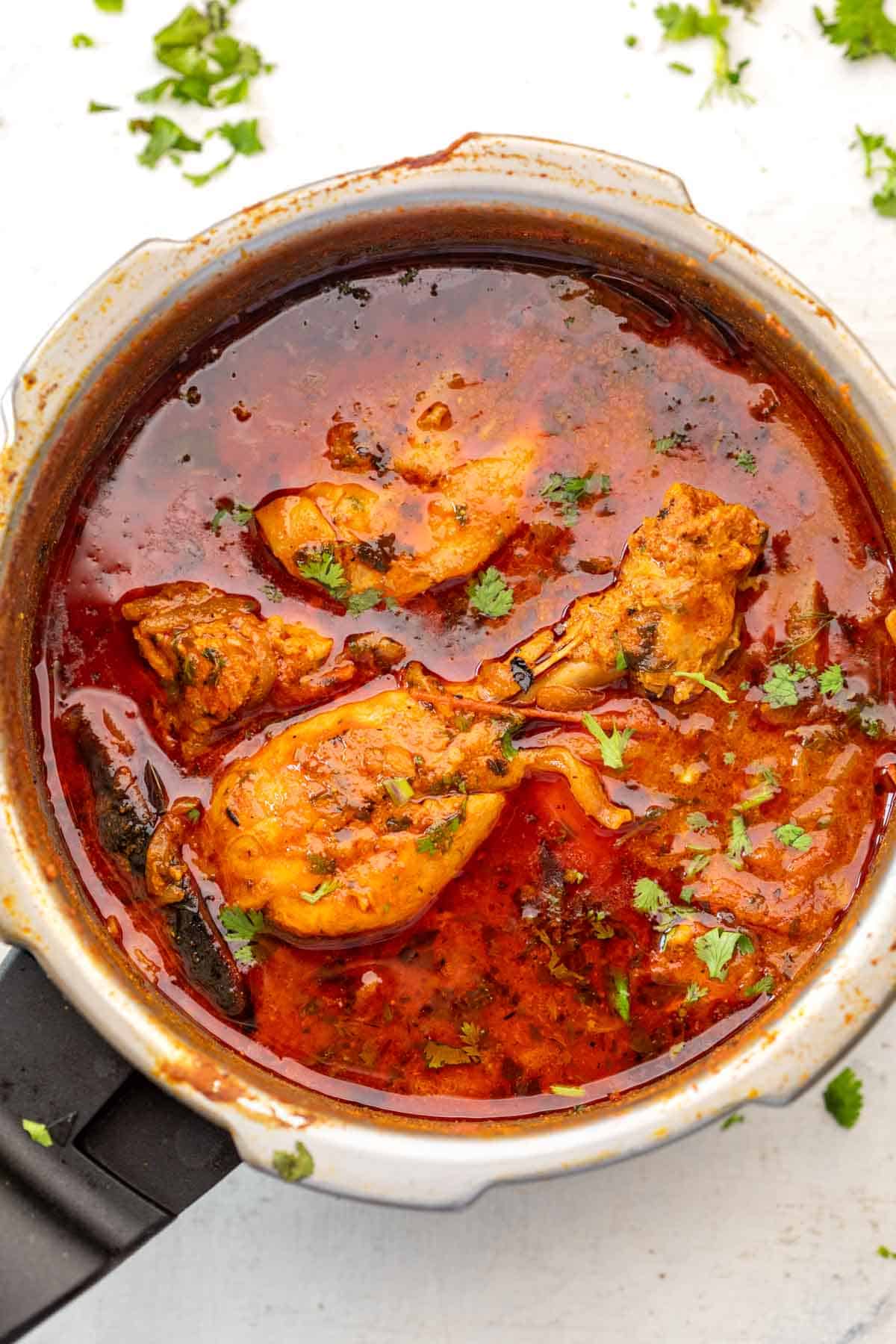 Pressure cooker chicken curry in a pressure cooker on a white background