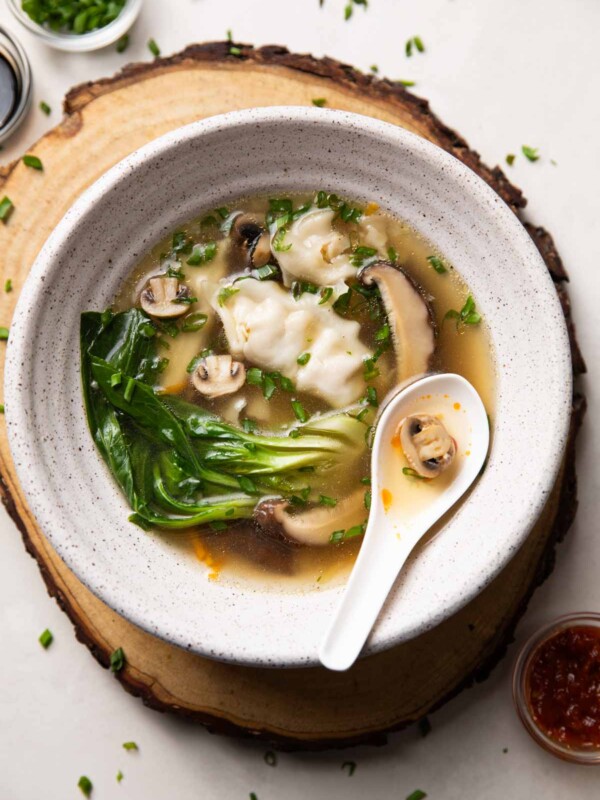Wanton soup served in a white bowl with spoon